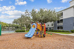 A playground with a blue slide and yellow climbing frame.