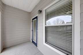 A white house with a blue door and a window with blinds.