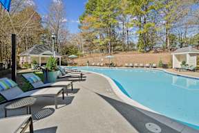 A pool surrounded by trees and a gazebo.