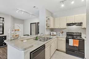A kitchen with a black oven and white cabinets.