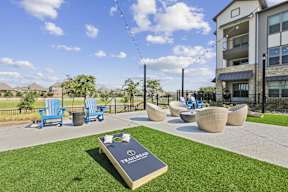 outdoor game lawn with fire pit and cornhole boards