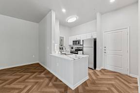 A kitchen with a white island and wooden floors.