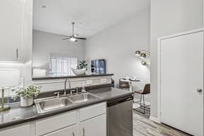 A modern kitchen with a stainless steel sink and a ceiling fan.