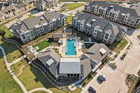 An aerial view of apartment buildings with a swimming pool in the center.