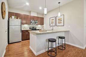 A kitchen with a white island and two black stools.