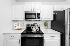 A black and white kitchen with a stove, oven, microwave, and refrigerator.