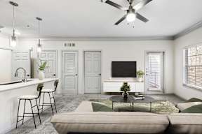 A living room with a grey couch, a white counter, and a ceiling fan.