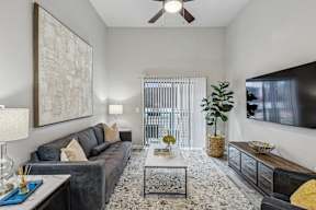 A living room with a black couch and a large painting on the wall.