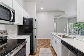 A kitchen with black appliances and white cabinets.