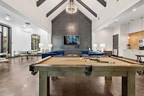 A pool table is in the middle of a room with a couch and a television.