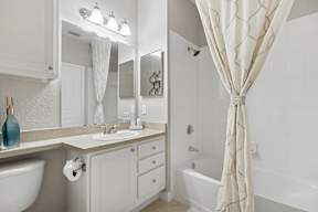 A white bathroom with a white tub and a white sink.