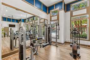 A gym with a variety of equipment including treadmills, weights, and exercise machines.