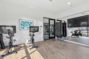 a gym with bikes and a tv and a glass door