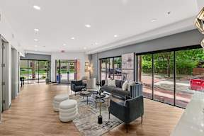 A modern living room with a black couch and a glass door leading to a balcony.