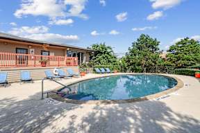 A small pool with a metal railing and a few chairs.