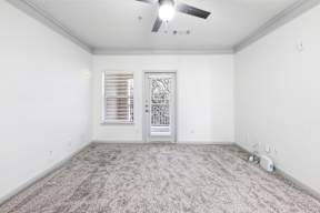 A room with a ceiling fan and a door with a window.