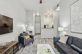 A living room with a grey couch, a coffee table, and a large painting on the wall.