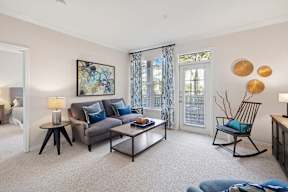 A living room with a grey couch, a coffee table, and a painting on the wall.