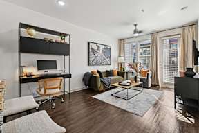 A modern living room with a black sofa and a wooden desk.