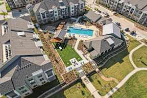 A bird's eye view of a residential area with houses, a swimming pool, and a green lawn.