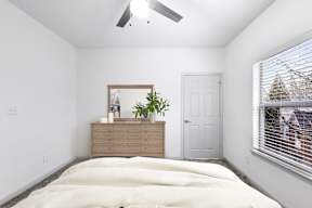A bedroom with a bed, dresser, and window.