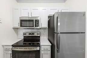 A kitchen with a stove, oven, microwave, and refrigerator.
