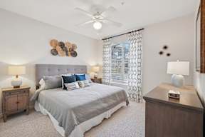 A bedroom with a bed, nightstands, and a ceiling fan.