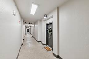 A long hallway with a door on the right and a light on the ceiling.