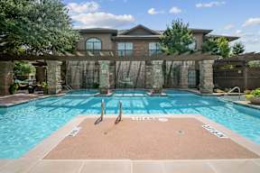 A large swimming pool with a diving board in front of a house.