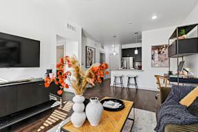 A living room with a white vase and orange flowers on a wooden table.