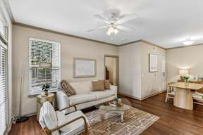 A living room with a white couch, a coffee table, and a ceiling fan.
