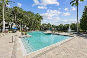 A large swimming pool surrounded by trees and a fountain.