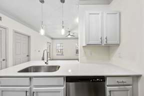 A kitchen with white cabinets and a stainless steel sink.