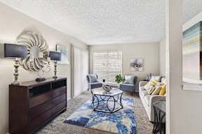 A living room with a white couch, a coffee table, and a large mirror on the wall.