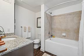 A bathroom with a white tub, sink, and toilet.