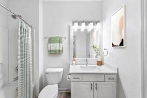 A white bathroom with a toilet, sink, and shower.
