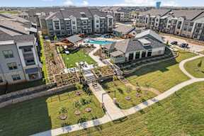 A bird's eye view of a residential area with apartment buildings, a swimming pool, and a playground.