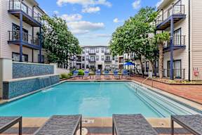 A swimming pool surrounded by apartment buildings and trees.