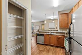 A kitchen with a refrigerator on the right and an open door to a pantry.