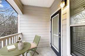 A small table with a vase and a book on it sits on a porch.