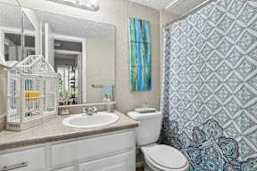 A bathroom with a white toilet, sink, and a birdcage on the counter.