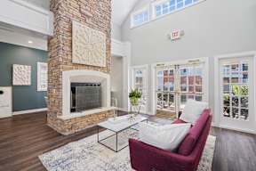 A living room with a red couch and a stone fireplace.