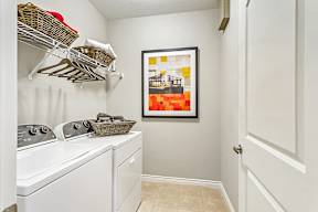 A laundry room with a washer and dryer and a basket on top of the dryer.