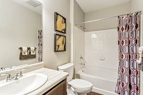 A bathroom with a white sink, toilet, and bathtub with a shower curtain.