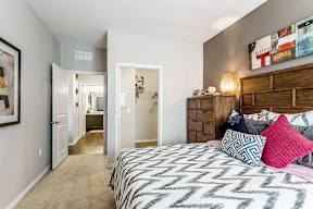 A bedroom with a patterned bedspread and a wooden dresser.