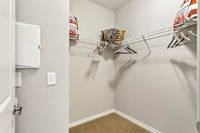 A white closet with a shelf and a white door.