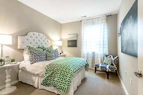 A bedroom with a white bed and green and white bedspread.