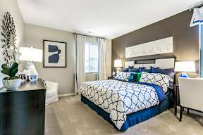 A bedroom with a large bed and a white chair.