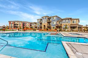 A large swimming pool in front of apartment buildings.