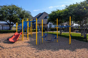 a playground with a swing set in front of a house